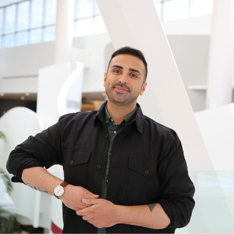 A photo of Bilal, smiling into the camera with short black hair, wearing a black shirt.