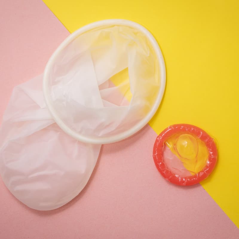 An internal condom and an external condom on a pink and yellow background