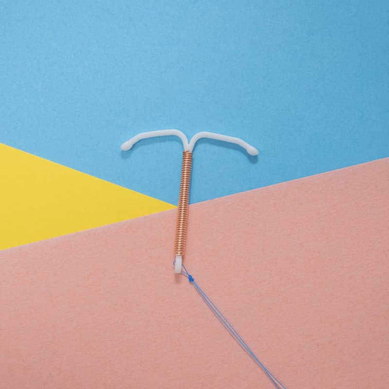 A copper IUD against a multi-coloured background.