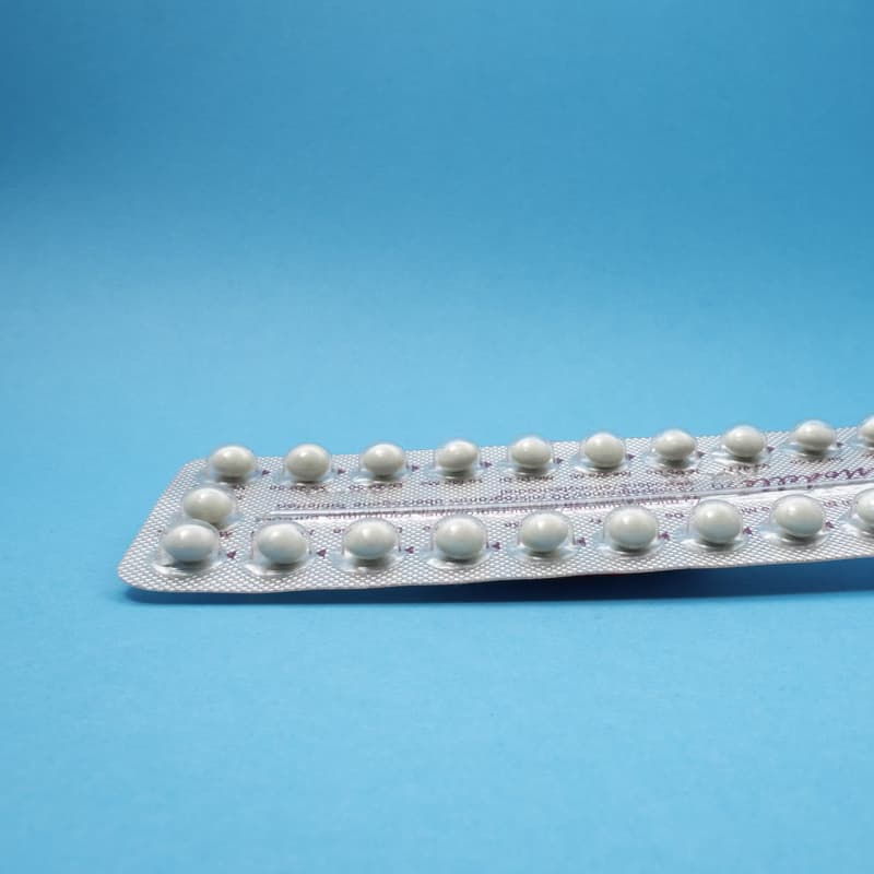a 21-day oral contraceptive pill packet on a blue background